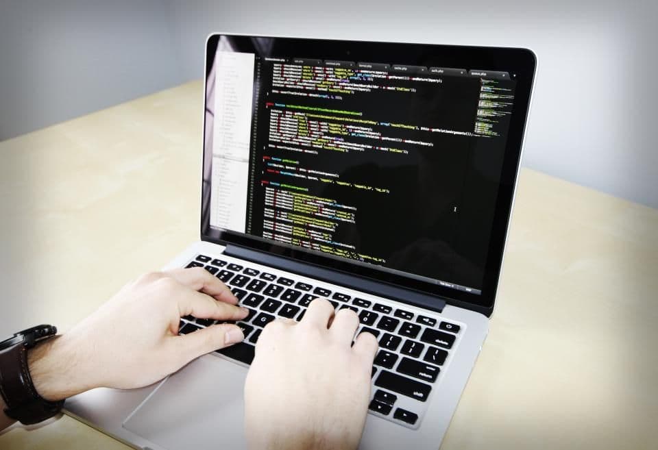 Hands on a keyboard in front of code